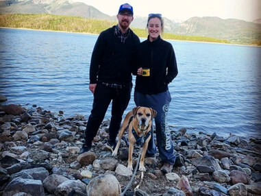 closer image of couple at the lake with dog